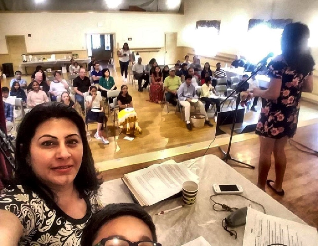 A view from the coach's table as a DSI student presents at the microphone to a seated audience