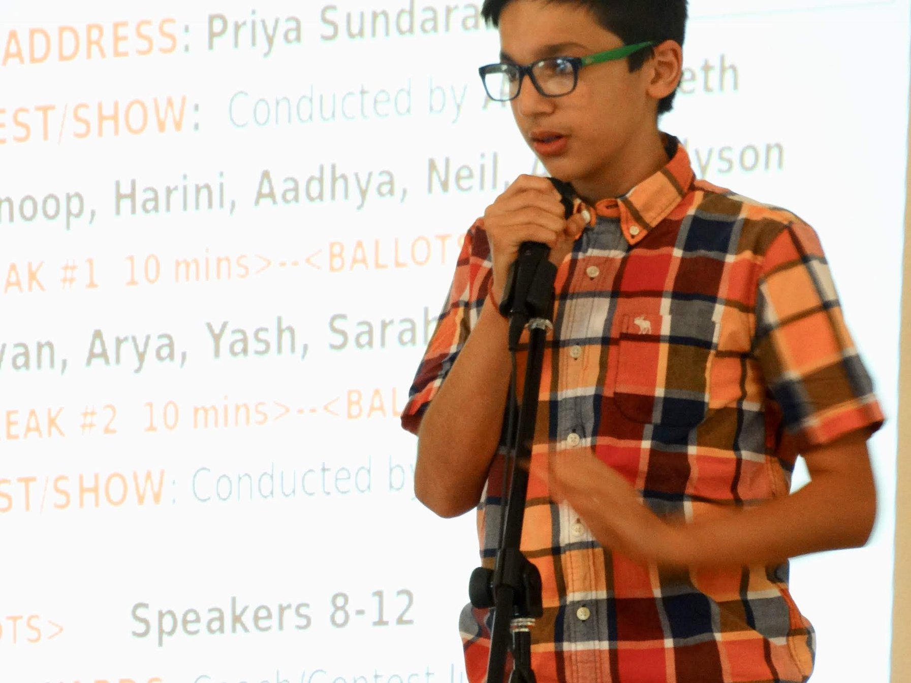 A DSI student speaking into a handheld microphone in front of the projected DSITalks agenda