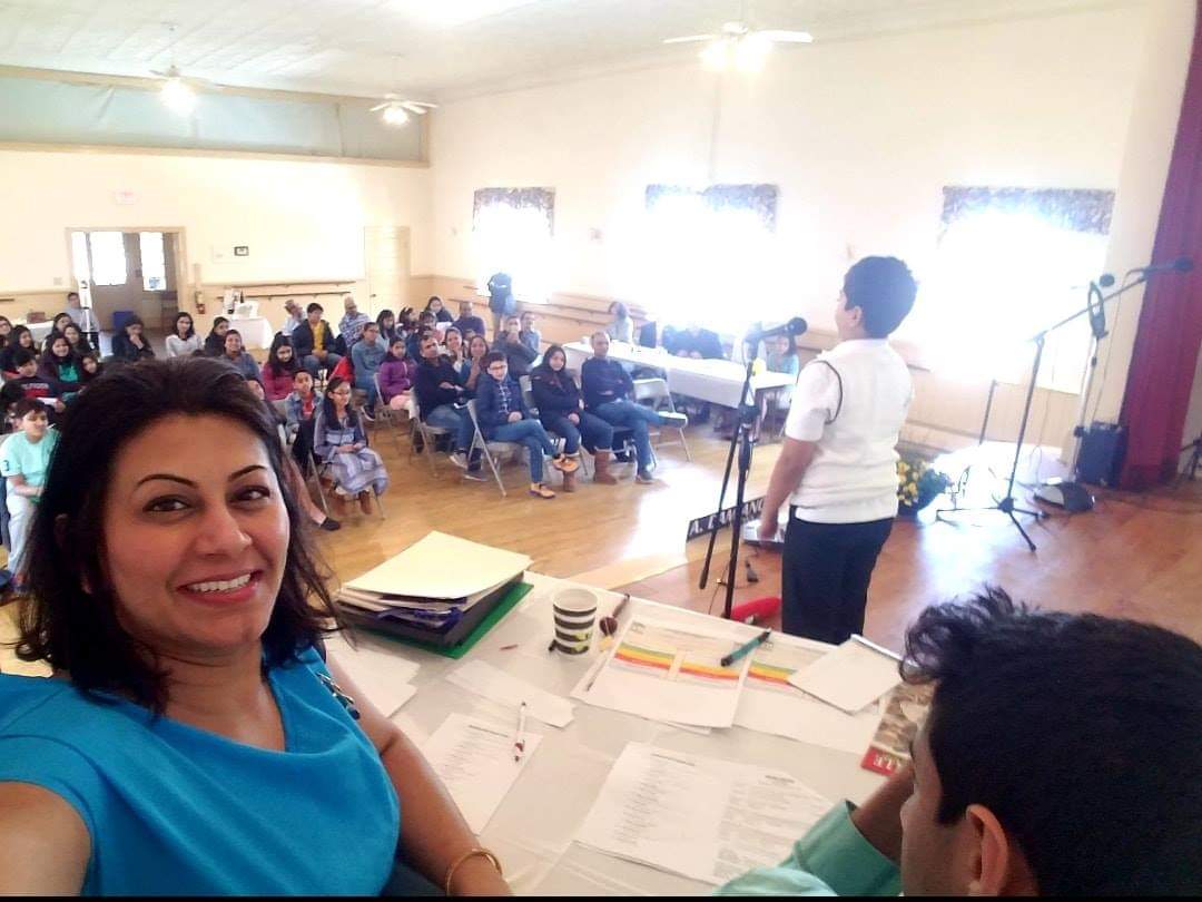 A DSI workshop in progress, a student speaking at the microphone while children and parents watch from rows of chairs