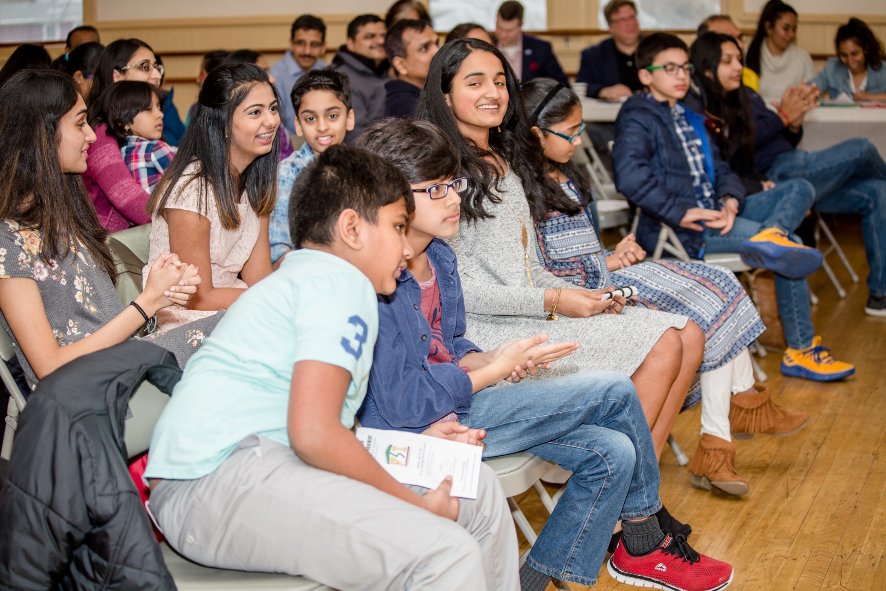 Children and parents seated in the audience at a DSITalks showcase, applauding